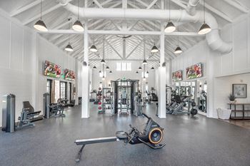 a large gym with weights machines and lights on the ceiling